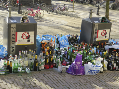 907198 Afbeelding van een grote hoeveelheid lege flessen, op straat gezet naast de volle ondergrondse glascontainers op ...